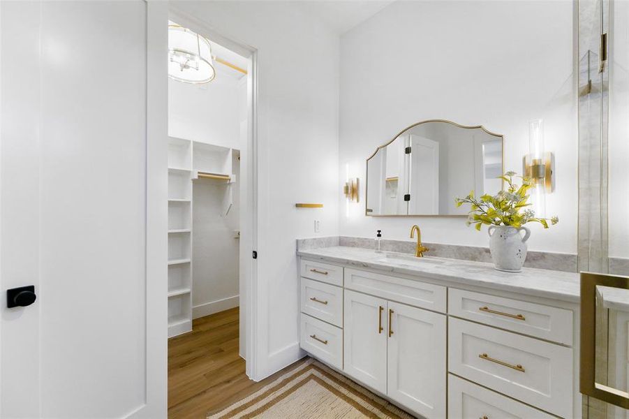 White vanity with gold hardware, a light-toned countertop, and an ornate mirror