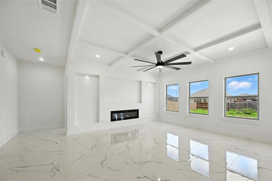 Unfurnished living room with recessed lighting, coffered ceiling, marble tiled floors, beamed ceiling, and a glass covered fireplace
