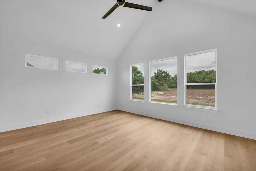 Unfurnished room featuring baseboards, ceiling fan, high vaulted ceiling, and light wood-type flooring Unfurnished room featuring baseboards, ceiling fan, high vaulted ceiling, and light wood-type flooring