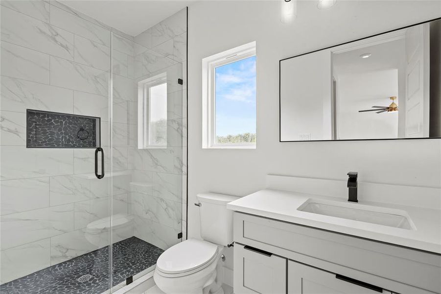 Bathroom featuring vanity, a marble finish shower, and a ceiling fan Bathroom featuring vanity, a marble finish shower, and a ceiling fan