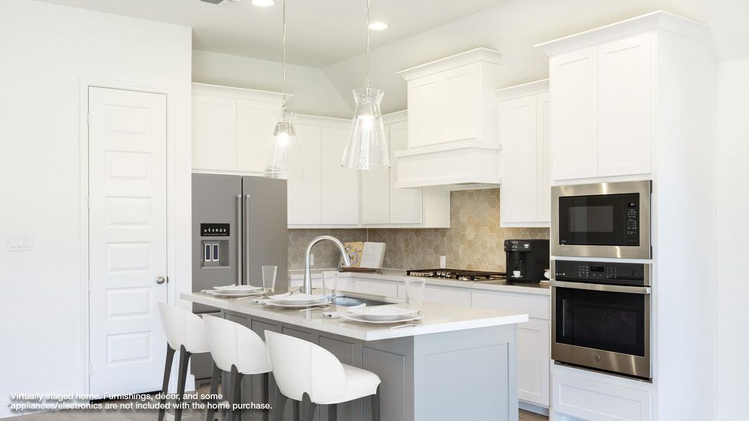 Kitchen featuring decorative backsplash, a breakfast bar, appliances with stainless steel finishes, hanging light fixtures, and white cabinetry Kitchen featuring decorative backsplash, a breakfast bar, appliances with stainless steel finishes, hanging light fixtures, and white cabinetry