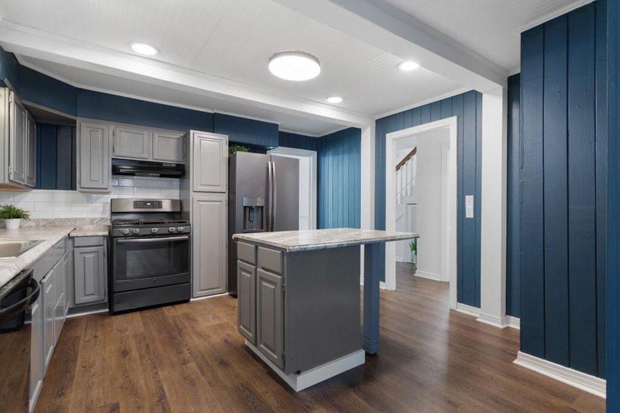Kitchen featuring appliances with stainless steel finishes, gray cabinetry, under cabinet range hood, a center island, and dark wood-style floors