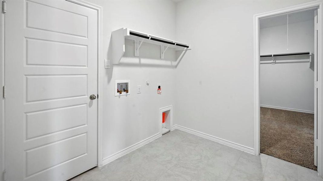 Laundry area with light-toned tile flooring and white walls
