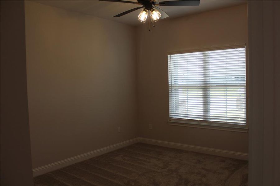 Unfurnished room featuring ceiling fan, baseboards, and dark carpet Unfurnished room featuring ceiling fan, baseboards, and dark carpet