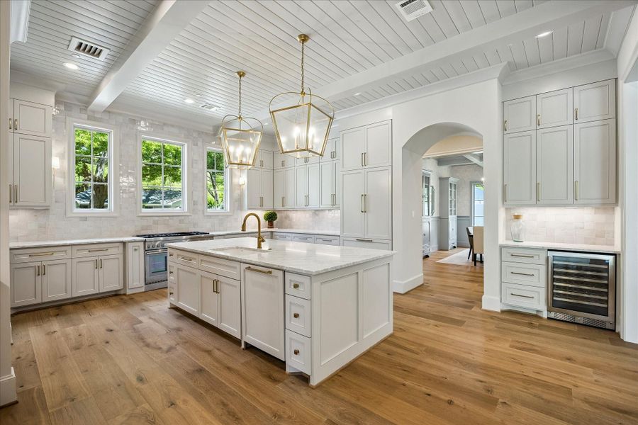 Kitchen perspective highlighting the stunning beamed ceiling detail, creating a striking architectural focal point. A dedicated coffee bar w/ built-in Avalon wine cooler adds both function & style to the space.
