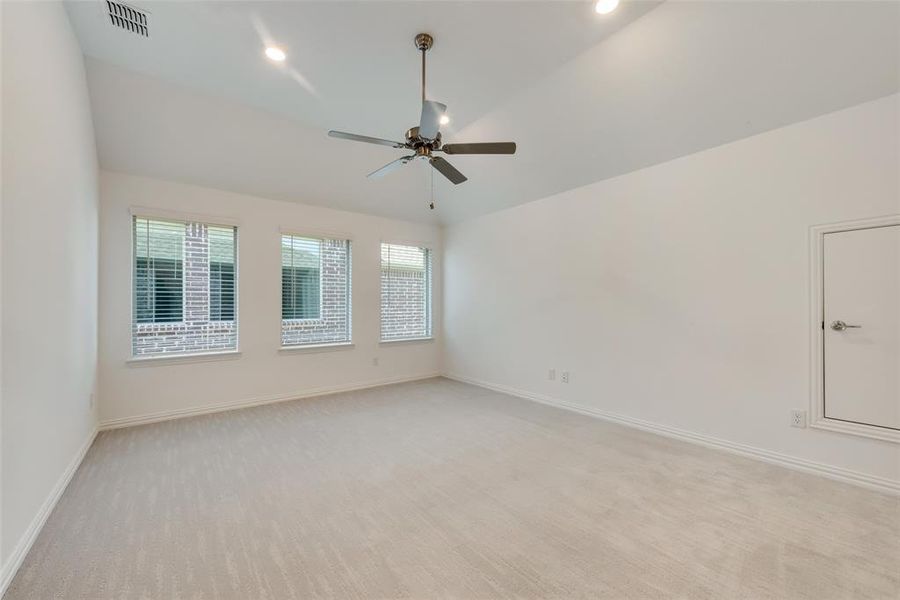 Spare room with ceiling fan, lofted ceiling, and light colored carpet