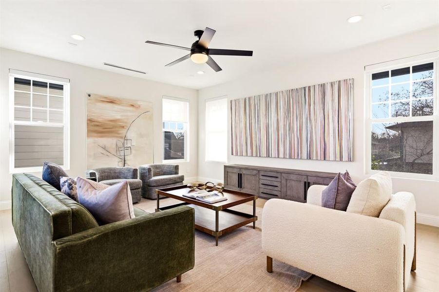 Living area featuring light wood-style flooring, a ceiling fan, and recessed lighting