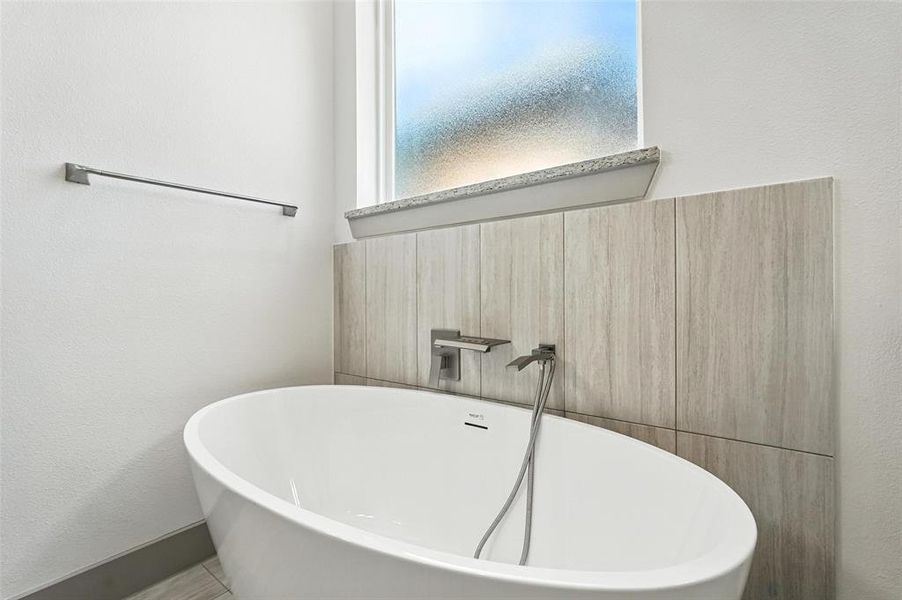 Bathroom with a freestanding tub and a textured wall Bathroom with a freestanding tub and a textured wall