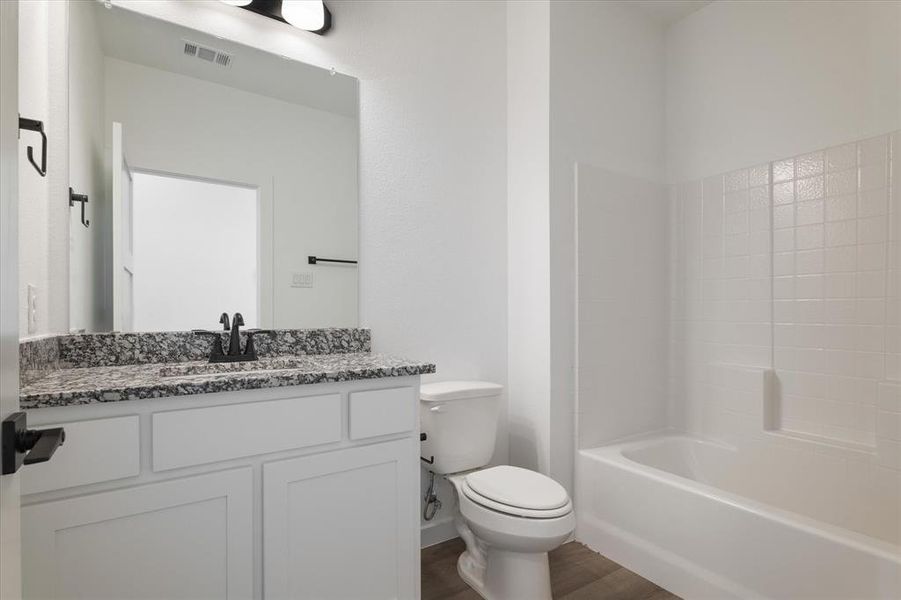 Full bathroom with vanity, hardwood / wood-style floors, toilet, and shower / washtub combination