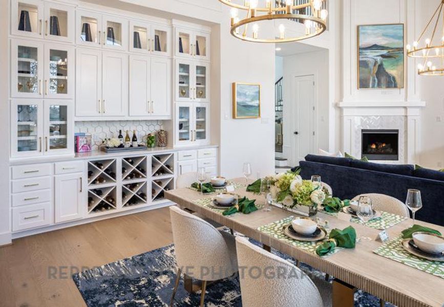 Dining space featuring a warm lit fireplace, wood finished floors, and a notable chandelier Dining space featuring a warm lit fireplace, wood finished floors, and a notable chandelier