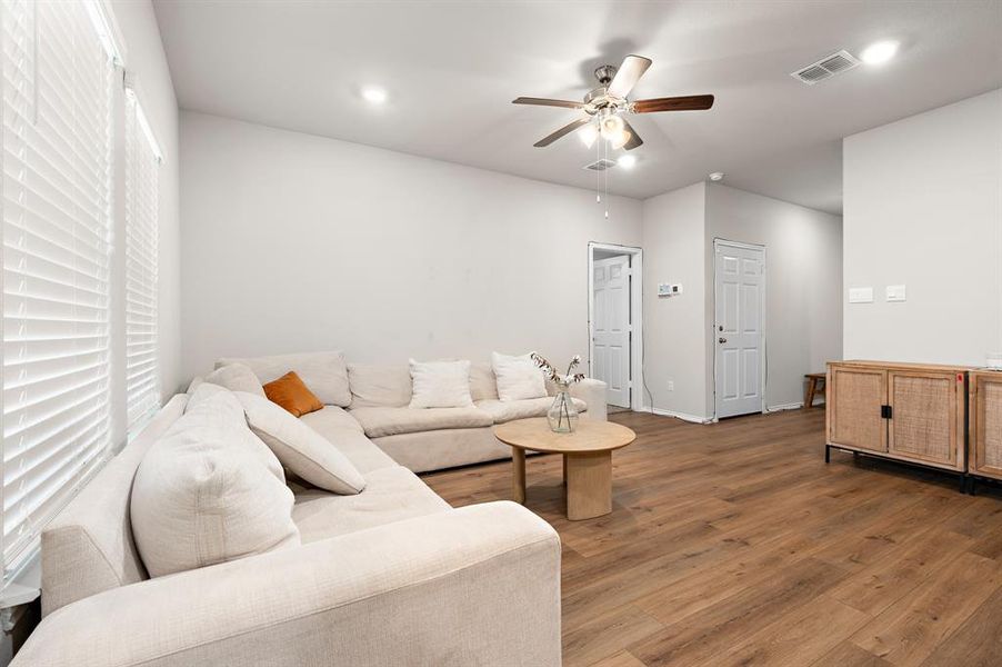 Living room with wood finished floors, a ceiling fan, and recessed lighting Living room with wood finished floors, a ceiling fan, and recessed lighting