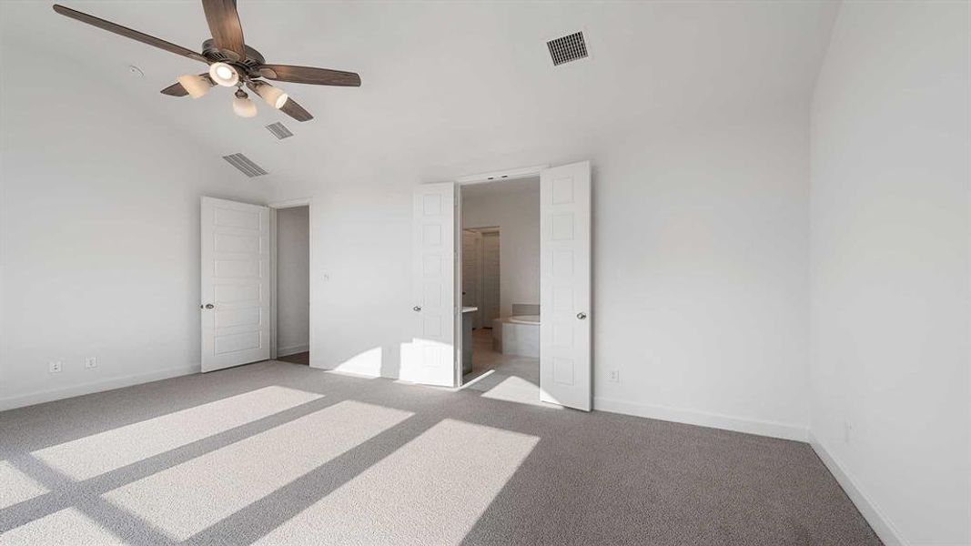 Unfurnished bedroom featuring ensuite bath, carpet, ceiling fan, and vaulted ceiling