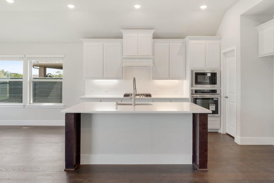 Kitchen with white cabinets, center island with sink, stainless steel double oven, and dark hardwood floors Kitchen with white cabinets, center island with sink, stainless steel double oven, and dark hardwood floors