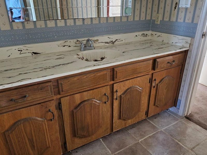 Bathroom featuring wallpapered walls, vanity, and tile patterned flooring Bathroom featuring wallpapered walls, vanity, and tile patterned flooring