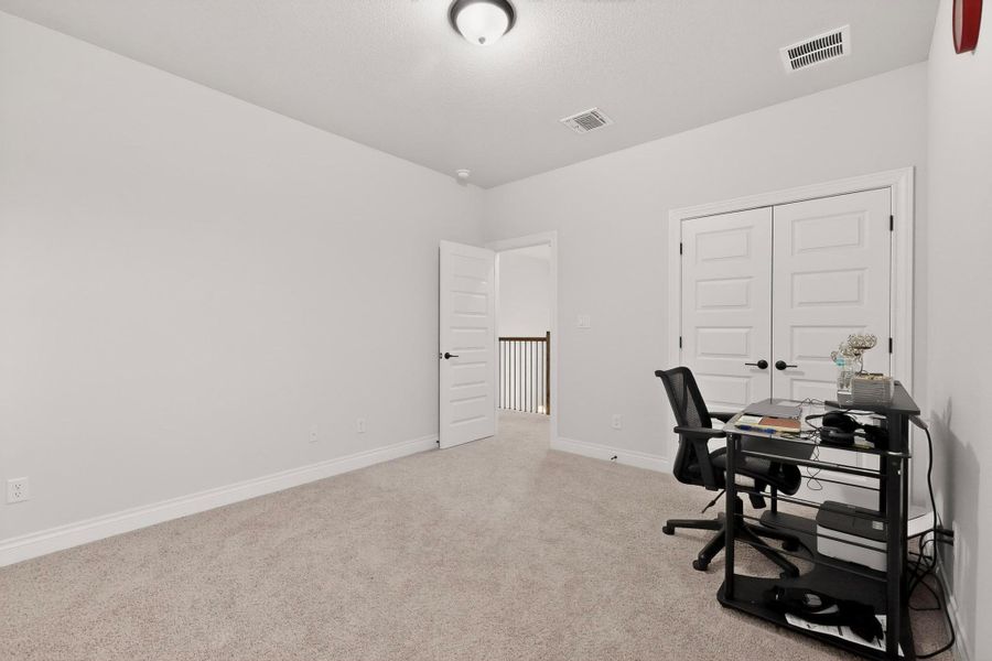 Home office with light colored carpet and baseboards