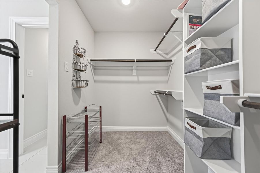Spacious primary bedroom walk-in closet featuring custom built-in shelving, high-end organizational storage systems, and bright recessed lighting; this alternate view captures the additional storage depth and efficient layout of the space. Spacious primary bedroom walk-in closet featuring custom built-in shelving, high-end organizational storage systems, and bright recessed lighting; this alternate view captures the additional storage depth and efficient layout of the space.
