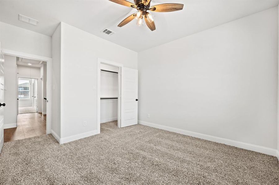 Unfurnished bedroom with light colored carpet, ceiling fan, and a closet