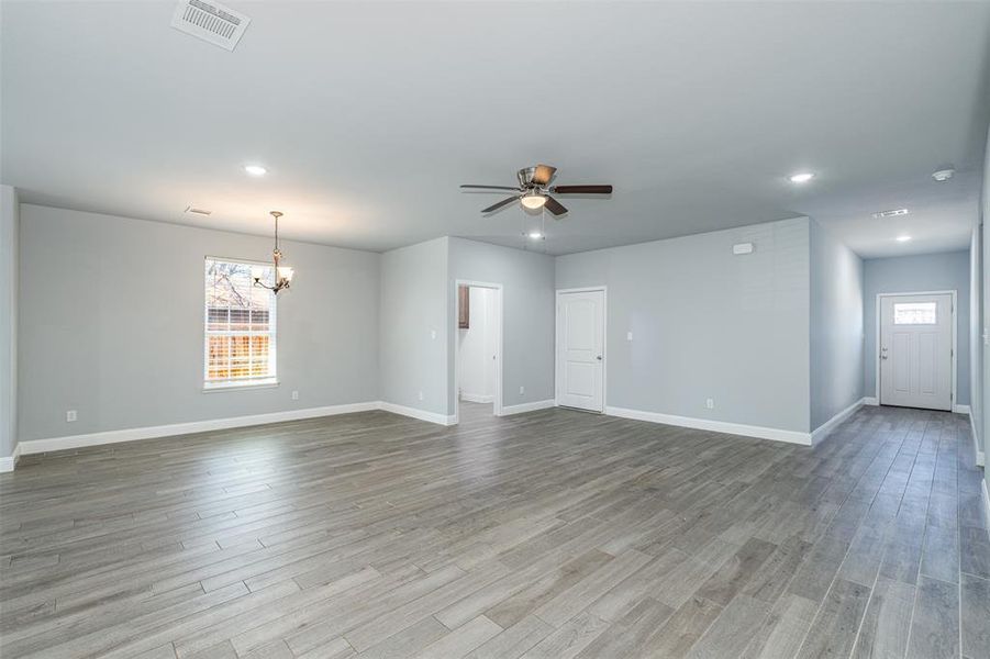 Spare room featuring recessed lighting, visible vents, wood finished floors, baseboards, and ceiling fan with notable chandelier