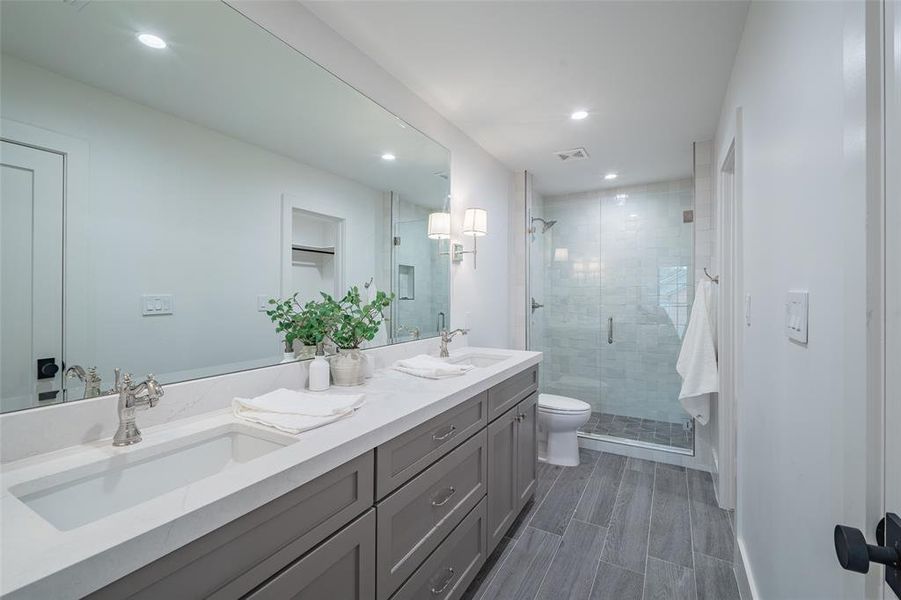 Bathroom featuring walk in shower, vanity, and toilet