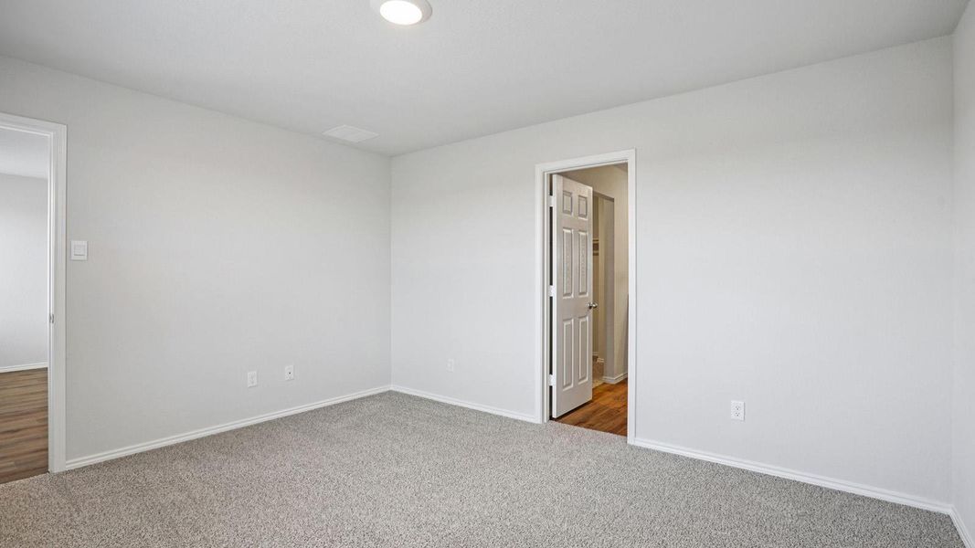A spacious room offers comfortable carpet flooring and a simple ceiling light fixture.