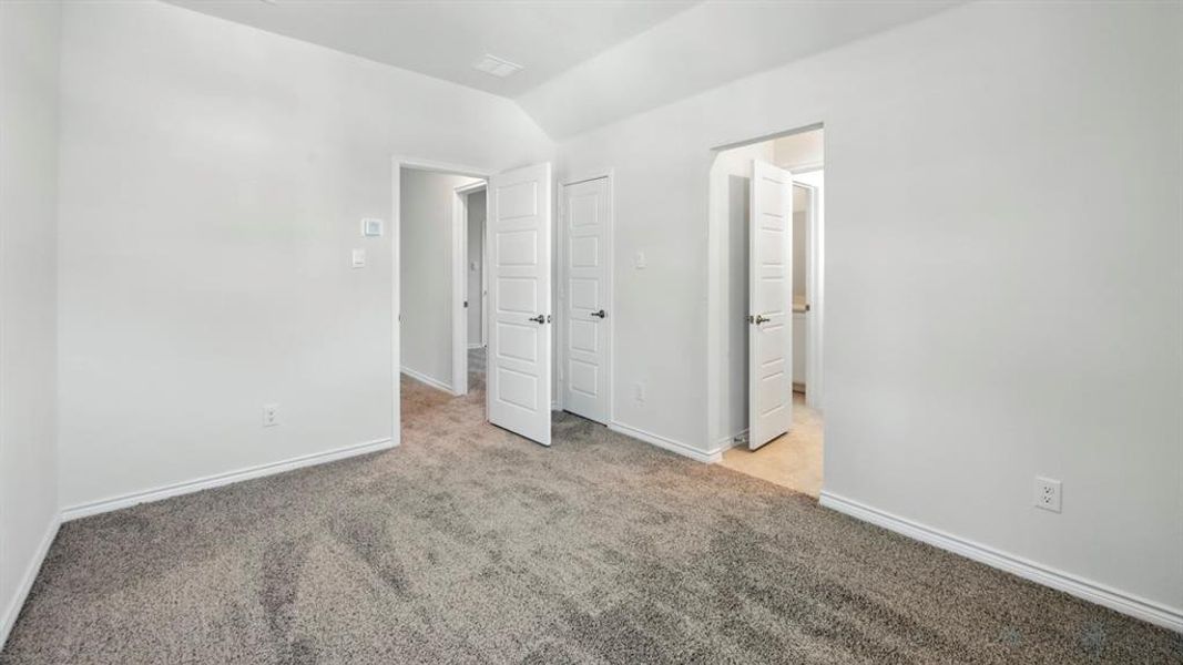 Unfurnished bedroom featuring light carpet and lofted ceiling Unfurnished bedroom featuring light carpet and lofted ceiling