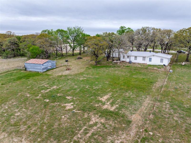 View of grassy yard featuring an outbuilding and view of scattered trees View of grassy yard featuring an outbuilding and view of scattered trees