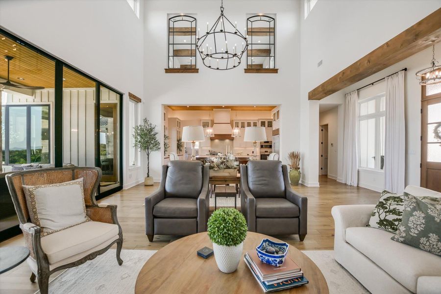 Living area with a chandelier, wood finished floors, a towering ceiling, and baseboards Living area with a chandelier, wood finished floors, a towering ceiling, and baseboards