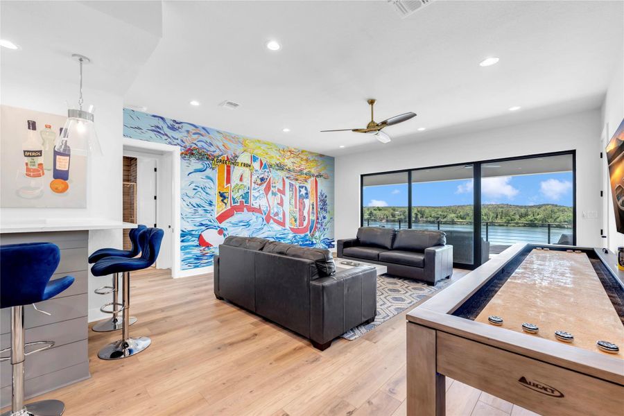 Living room two: Gleaming wood floors and floor-to-ceiling glass doors frame tranquil waterfront views in this open space.