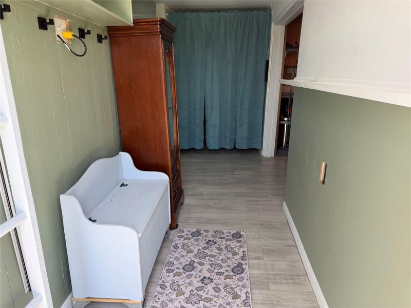 Welcoming entryway with durable flooring and convenient wall hooks, leading to an adjoining versatile space.
