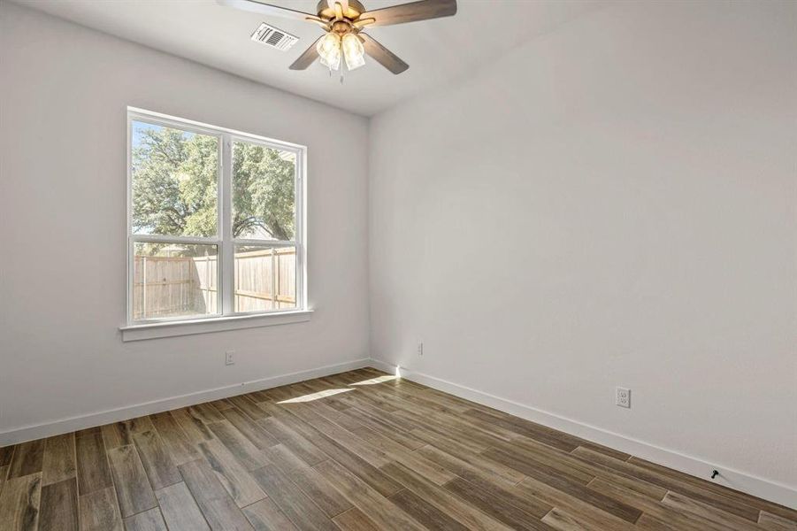 Unfurnished room featuring a ceiling fan, dark wood-style floors, and baseboards