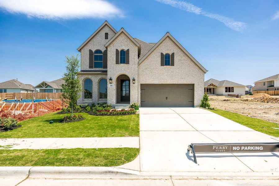 French country style house with brick siding, an attached garage, and concrete driveway French country style house with brick siding, an attached garage, and concrete driveway
