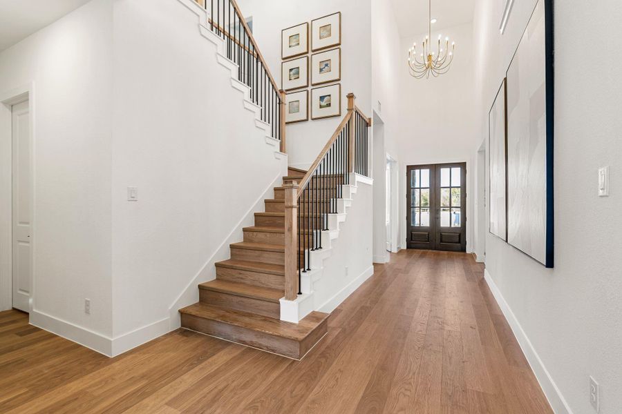 An eye-catching modern chandelier adds a touch of sophistication, while the open second-floor overlook enhances the home’s airy, open-concept design—setting the tone for the refined living spaces beyond.