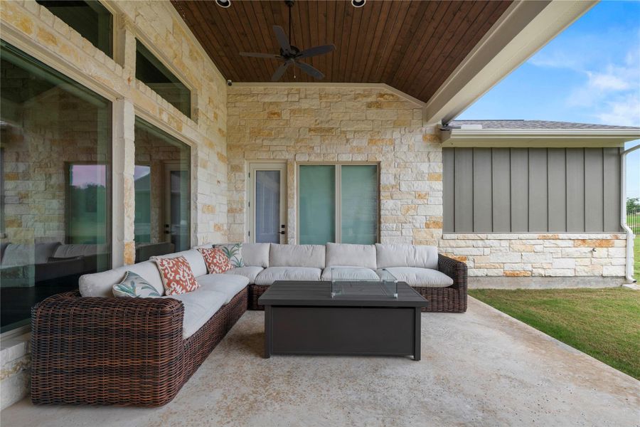 An inviting covered back patio featuring a rich wood plank ceiling and elegant stone wall accents. An inviting covered back patio featuring a rich wood plank ceiling and elegant stone wall accents.