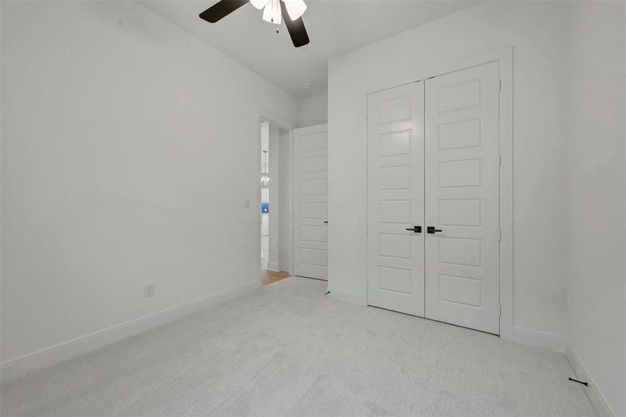 Bedroom featuring light-colored carpeting, white walls, and a ceiling fan with integrated lighting