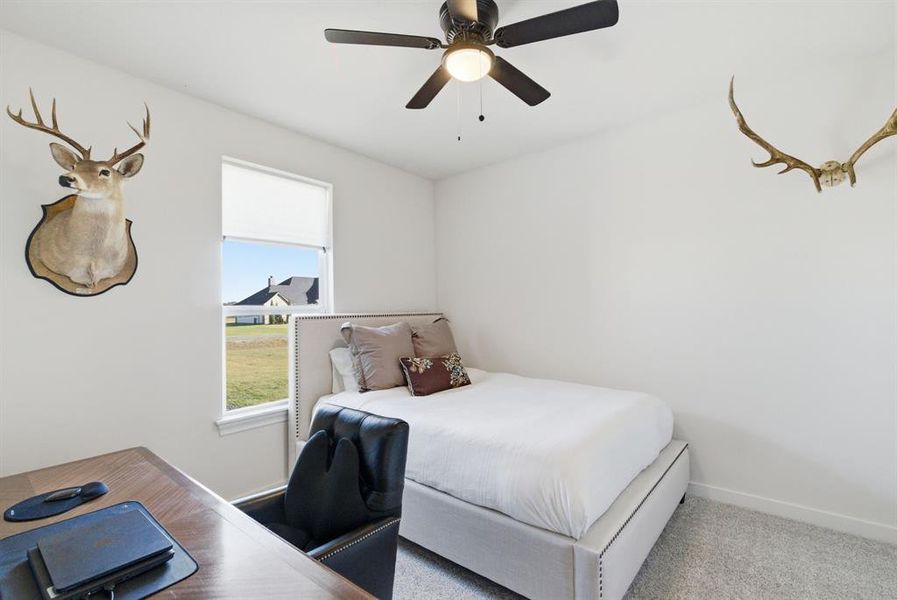 Carpeted bedroom featuring ceiling fan and baseboards