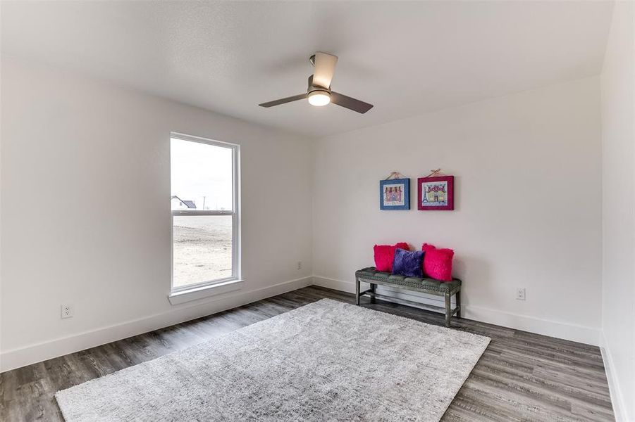 Sitting room with dark wood-style floors, ceiling fan, and baseboards