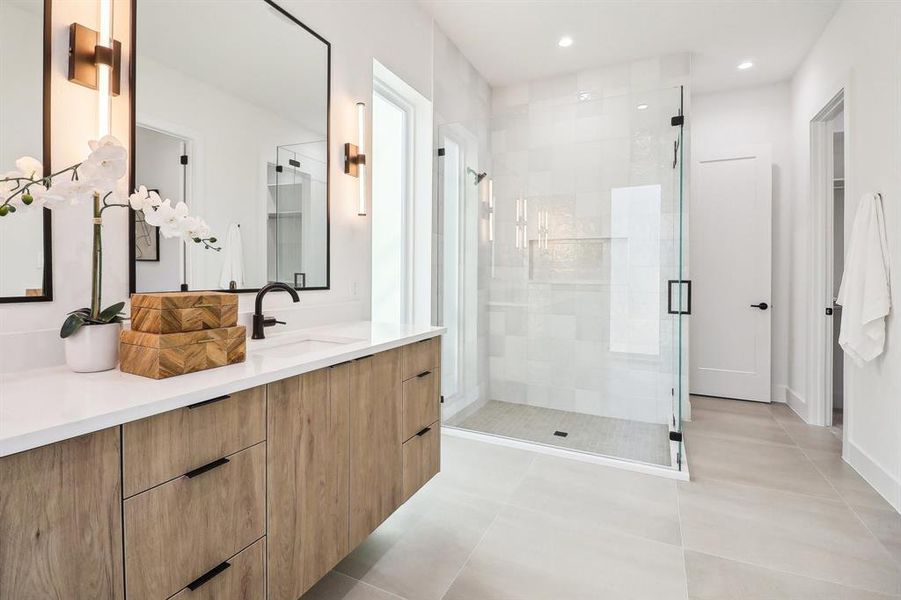 Bathroom featuring a shower with door, vanity, and tile patterned floors