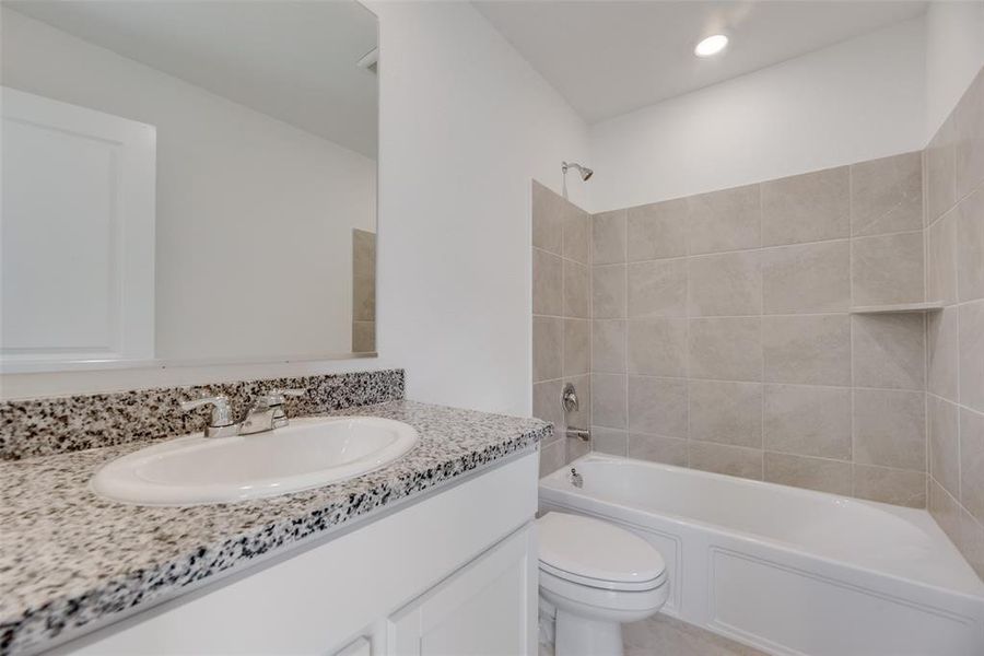 Full bathroom featuring vanity, tiled shower / bath combo, and toilet