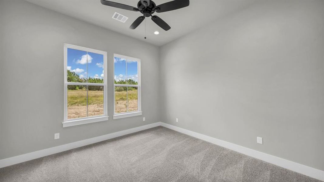 Spacious room featuring two large windows, light gray wall paint, and gray carpet flooring