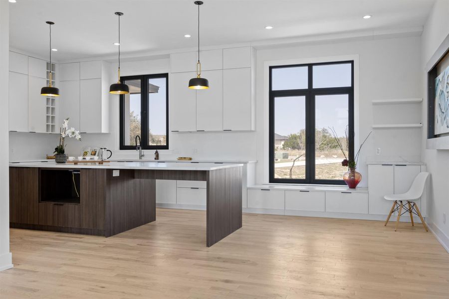 Kitchen featuring plenty of natural light, white cabinets, modern cabinets, and light countertops