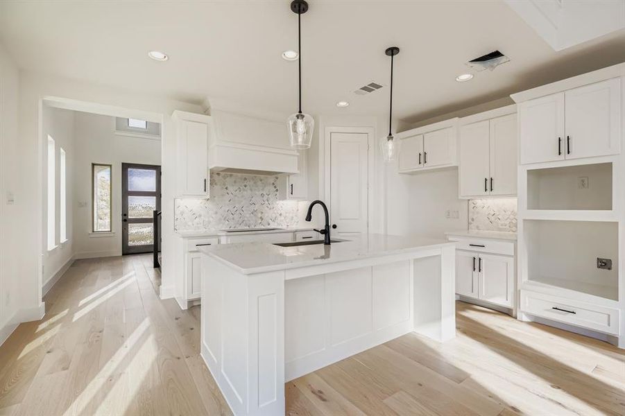 Kitchen featuring decorative backsplash, white cabinetry, a kitchen island with sink, and recessed lighting Kitchen featuring decorative backsplash, white cabinetry, a kitchen island with sink, and recessed lighting