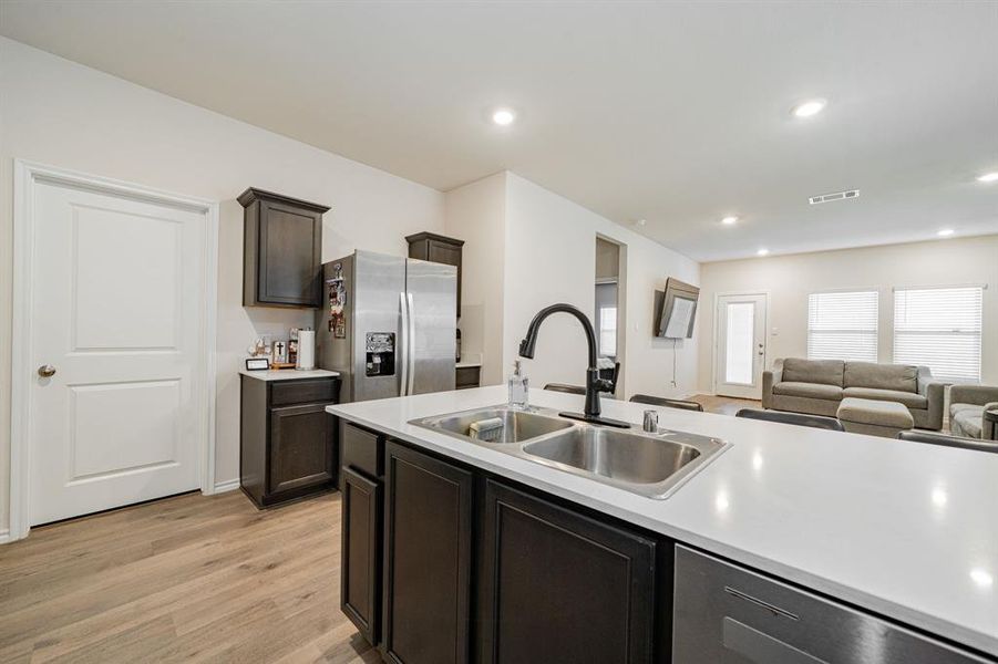 Kitchen featuring open floor plan, appliances with stainless steel finishes, dark brown cabinets, light countertops, and recessed lighting Kitchen featuring open floor plan, appliances with stainless steel finishes, dark brown cabinets, light countertops, and recessed lighting