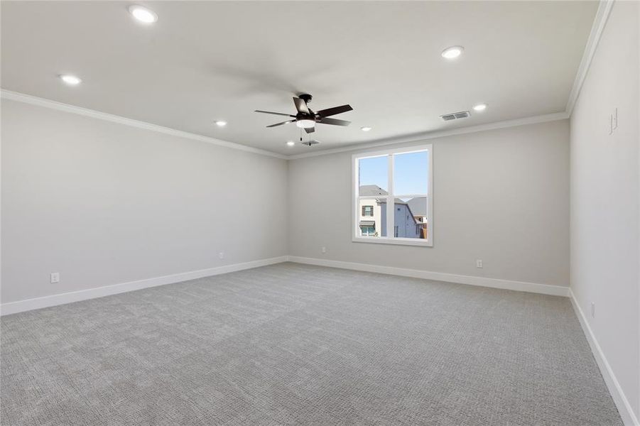 Spacious room featuring light gray carpeting, recessed lighting, a ceiling fan, crown molding, and a large window
