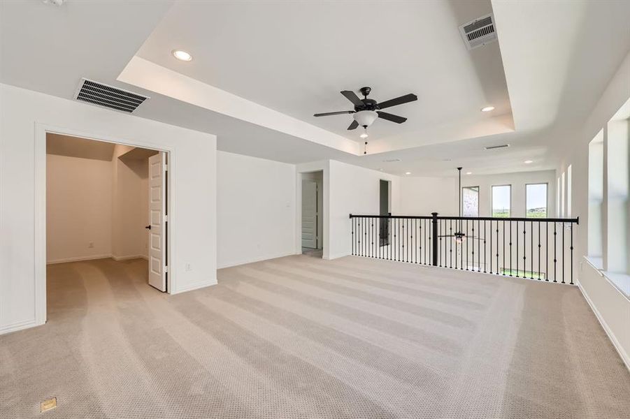 Game room with ceiling fan, a raised ceiling, and light carpet