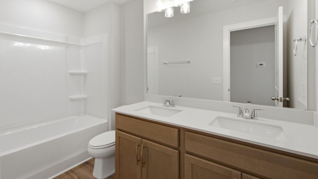 Secondary bathroom with elevated finishes such as dual vanities and bathtub