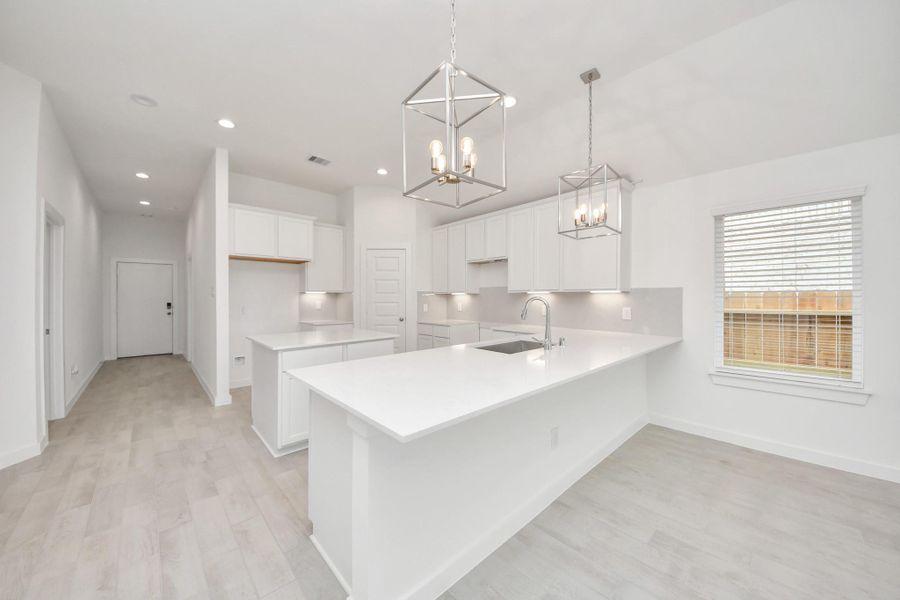 The kitchen is a culinary haven, featuring granite countertops, a tile backsplash, stainless steel appliances, 42” upper cabinets, and undercabinet lighting. Sample photo of completed home with similar floor plan. Actual colors and selections may vary. The kitchen is a culinary haven, featuring granite countertops, a tile backsplash, stainless steel appliances, 42” upper cabinets, and undercabinet lighting. Sample photo of completed home with similar floor plan. Actual colors and selections may vary.