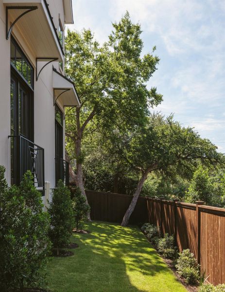 Enclosed side yard below the Juliet balconies off the living room. Landscape lighting, irrigation, and upgraded wood privacy fence.