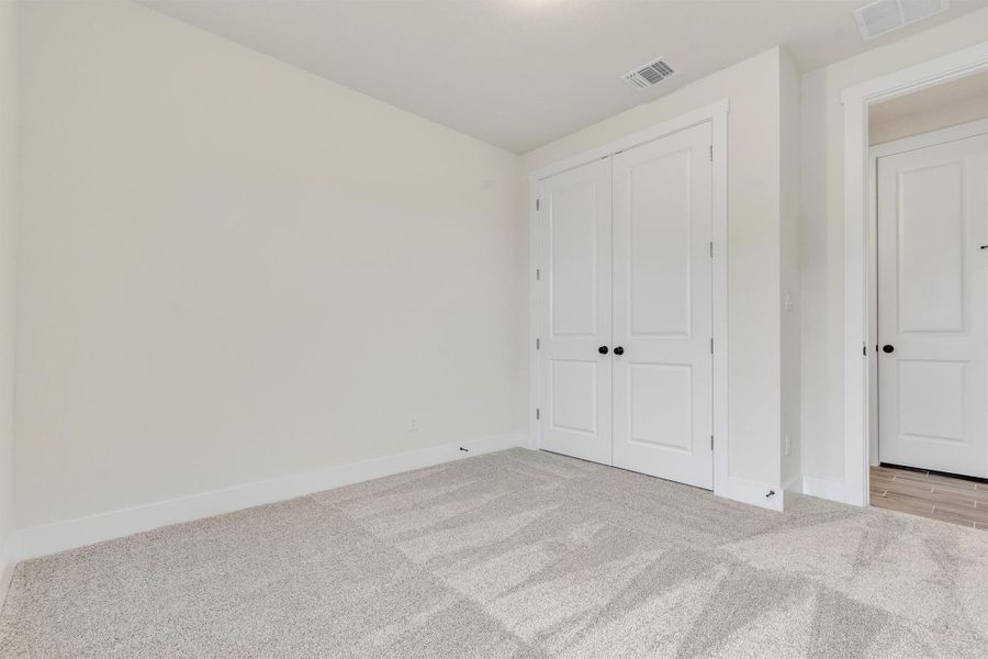 A well-lit bedroom features ample closet space and plush carpeting, creating a serene personal retreat.