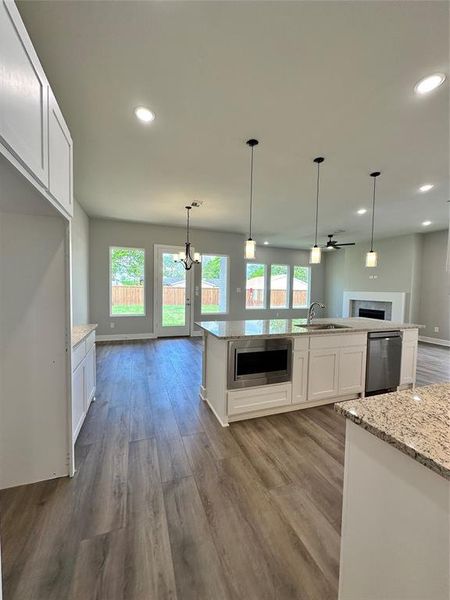 Kitchen featuring white cabinets, dishwashing machine, light stone countertops, and hardwood / wood-style flooring