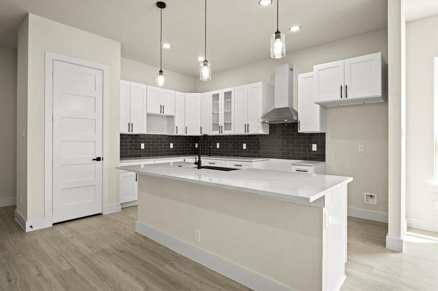 Kitchen with pendant lighting, decorative backsplash, white cabinetry, an island with sink, and recessed lighting Kitchen with pendant lighting, decorative backsplash, white cabinetry, an island with sink, and recessed lighting